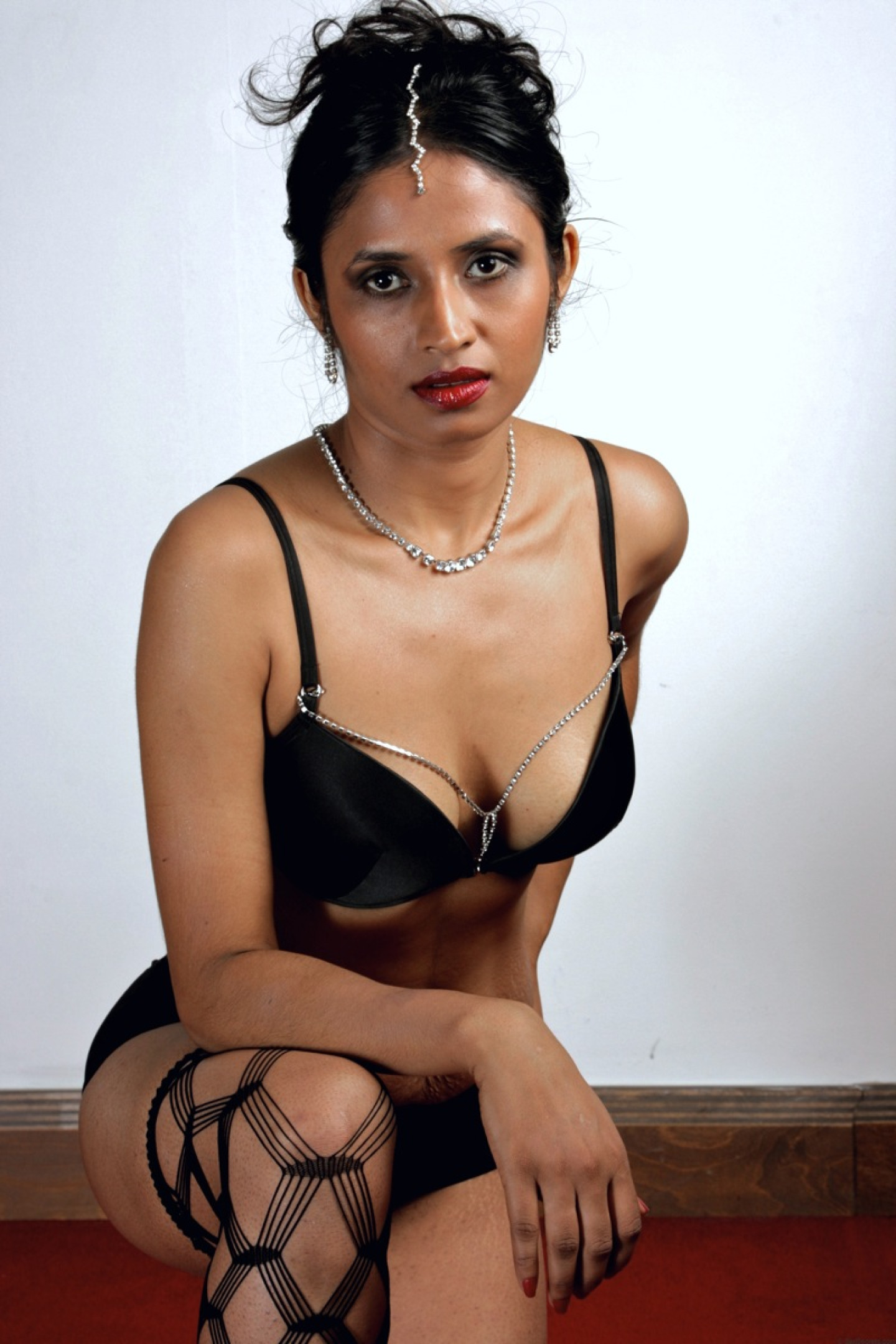Beautiful Indian female sheds an overcoat to model in underwear and stockings