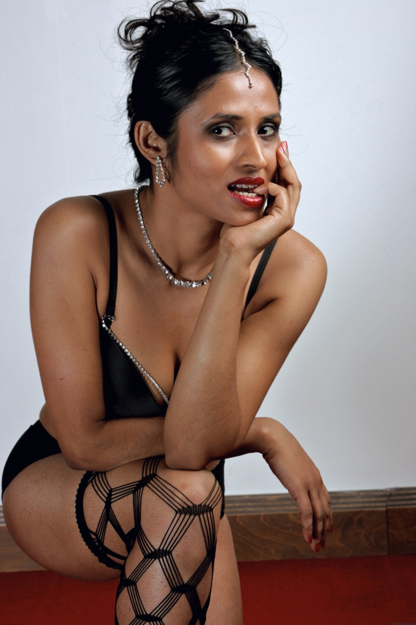 Beautiful Indian female sheds an overcoat to model in underwear and stockings
